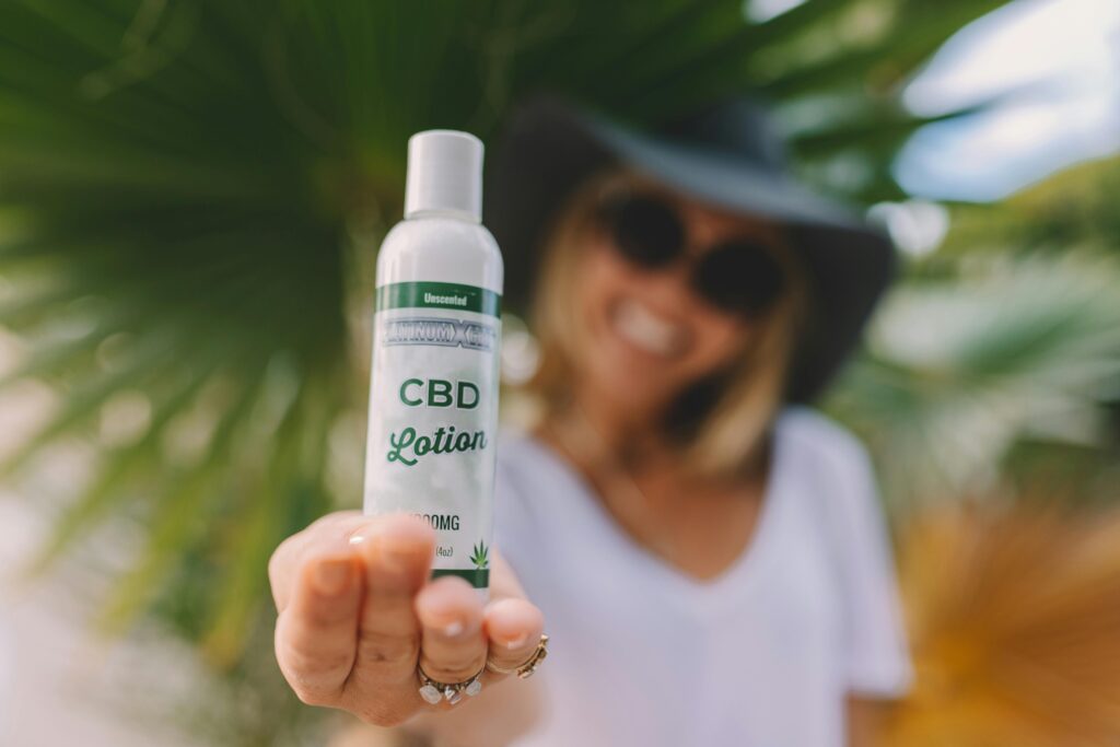 Shallow Focus Photo of Woman Holding CBD Lotion Bottle